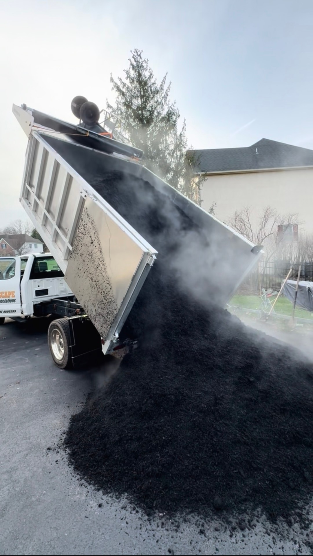 Larson Landscape dump truck delivering a steaming load of fresh black mulch