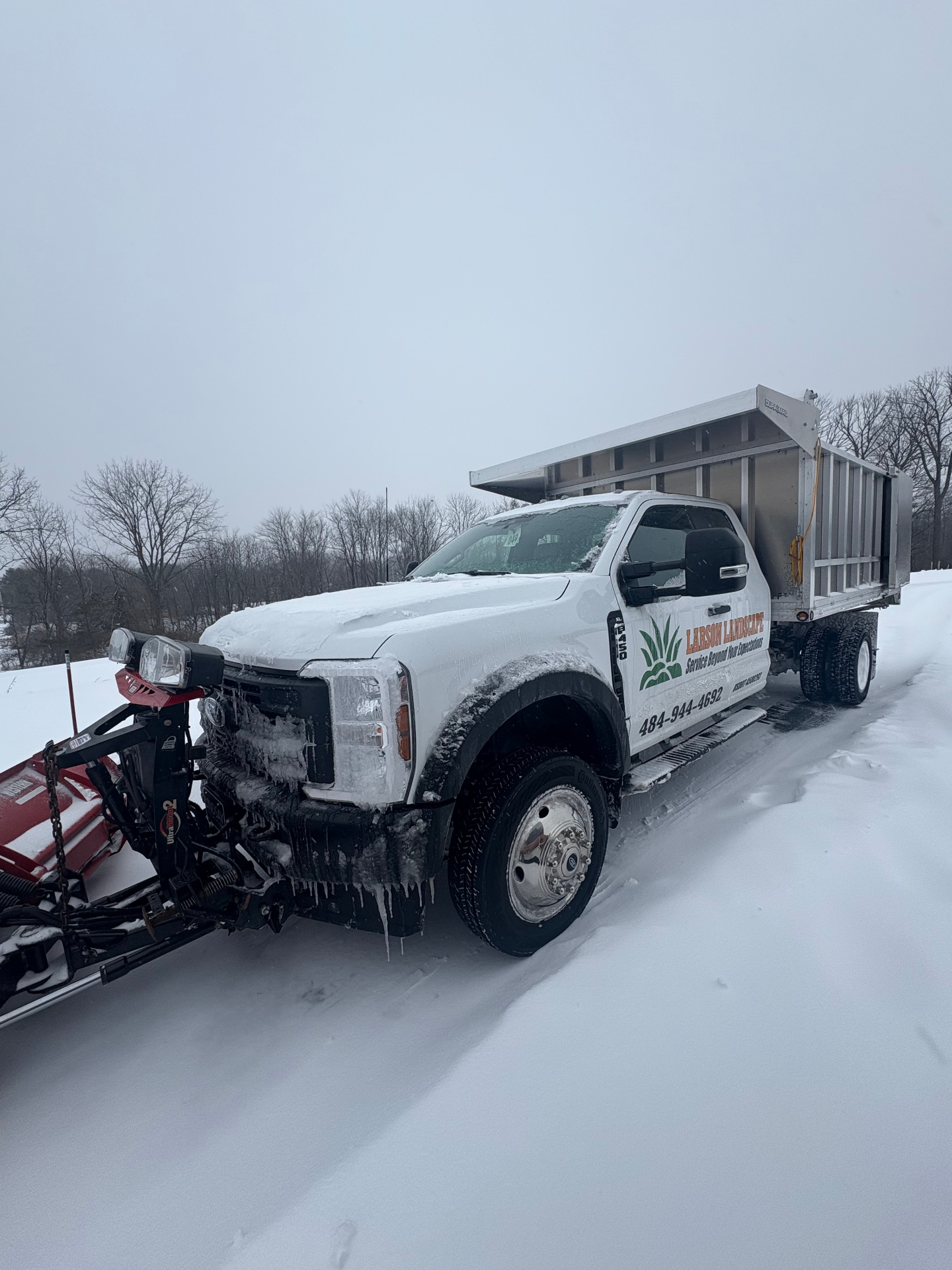 Larson Landscape branded plow truck parked in fresh snow, ready for commercial snow removal